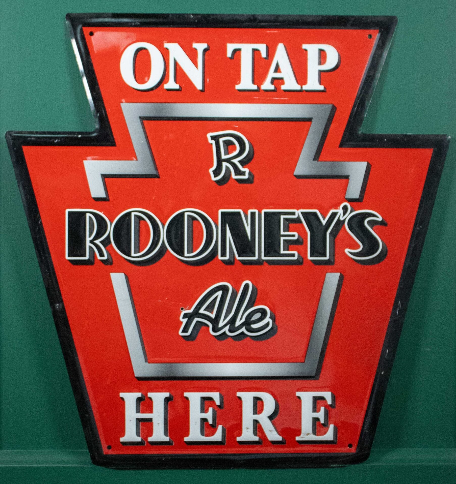 Rooney’s Ale “On Tap Here” Embossed Metal Keystone Bar Sign